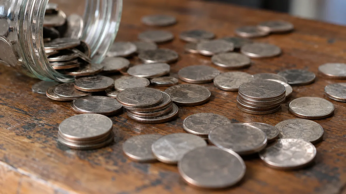How many different quarters are there: old and new quarters spilling from a glass jar onto a wooden table